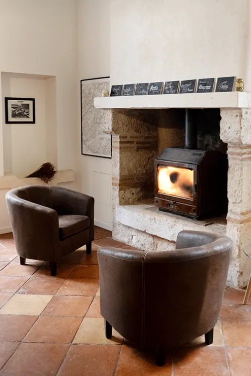 Salon avec poêle à bois et fauteuils club, gîte La Métairie Castelculier